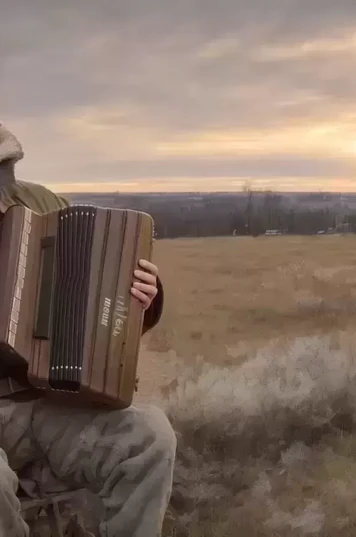 夕阳下中年人头戴皮帽拉手风琴